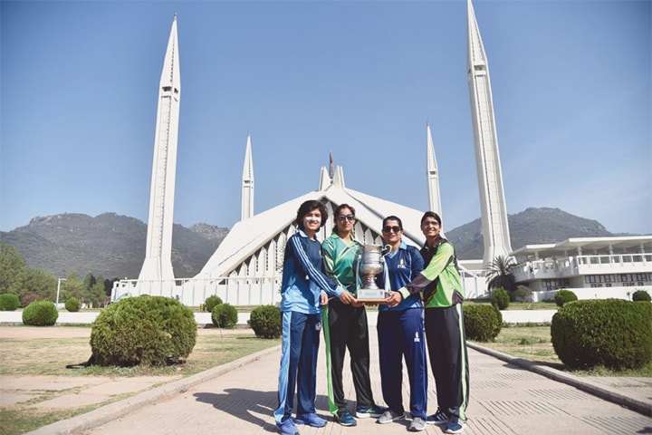 Rival skippers hold the Women’s Inter-departmental T20 Cricket Championship trophy in front of the Shah Faisal Mosque on Tuesday.—Courtesy PCB