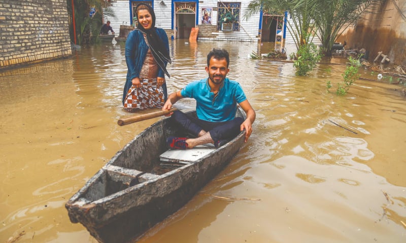 AHVAZ: A man sits in a boat at his flooded garden in a village near Ahvaz.—AFP