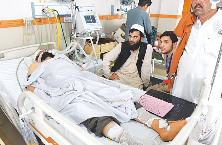 Relatives sit in a Quetta hospital on Saturday near a man who was injured in the suicide attack a day before.—AFP