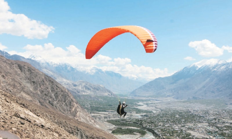 A paraglider flies over Gilgit.—Dawn