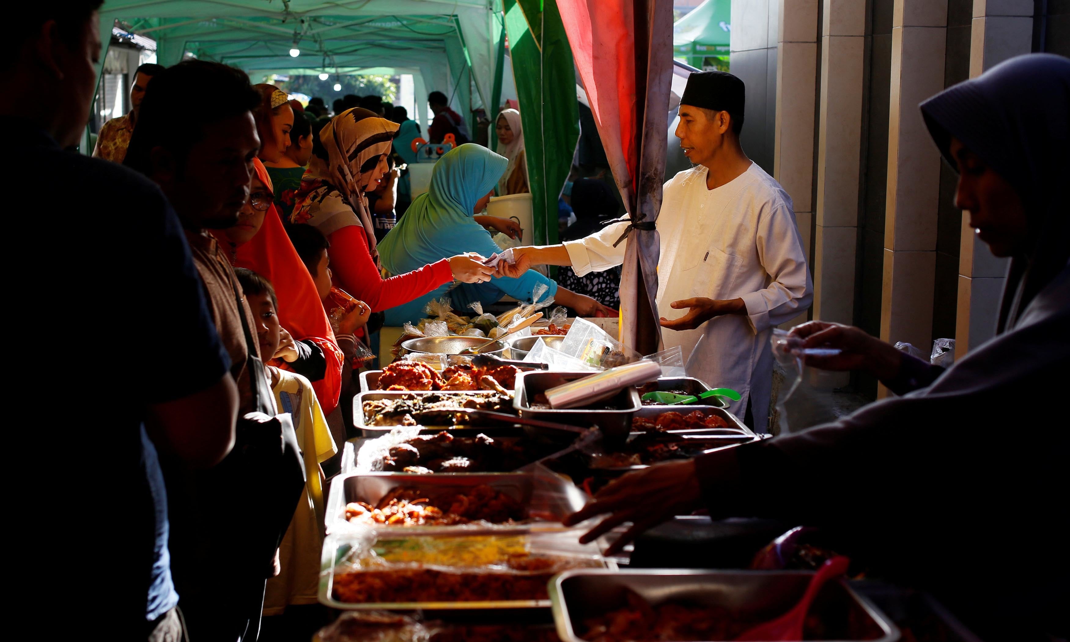 Indonesian Muslims buy food for iftar at a traditional food market during the first day of Ramazan in Denpasar, Bali, Indonesia. — Reuters