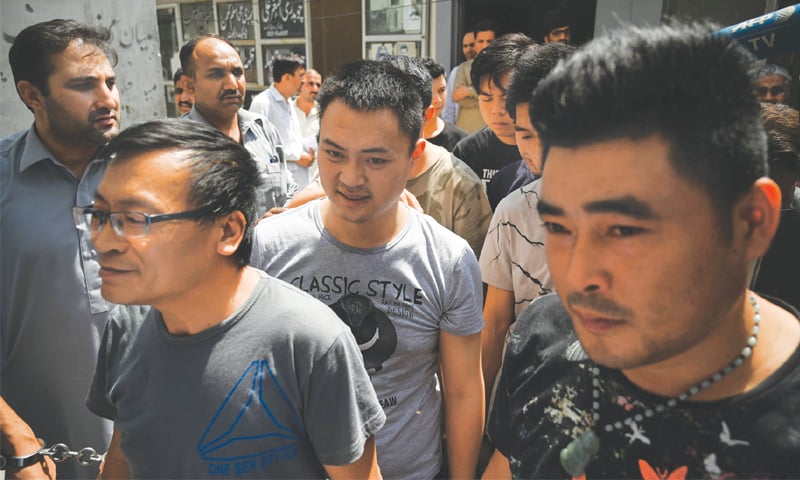 Detained Chinese nationals walk together as they arrive at a court after being arrested by the FIA in the bride trafficking case on Thursday.—AFP Detained Chinese nationals walk together as they arrive at a court after being arrested by the FIA in the bride trafficking case on Thursday.—AFP