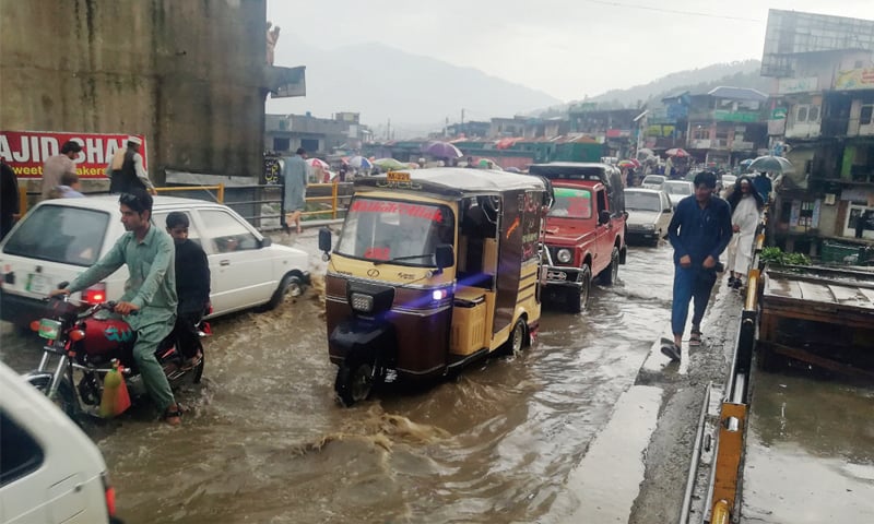 Vehicles pass through rainwater in Battagram Bazaar on Karakoram Highway on Friday. &mdash; Dawn