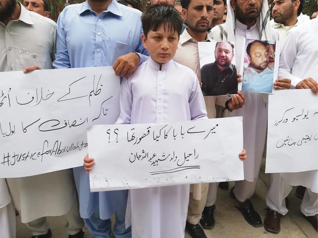 Son of the deceased holds a placard at the protest in Bajaur on Friday. &mdash;Dawn