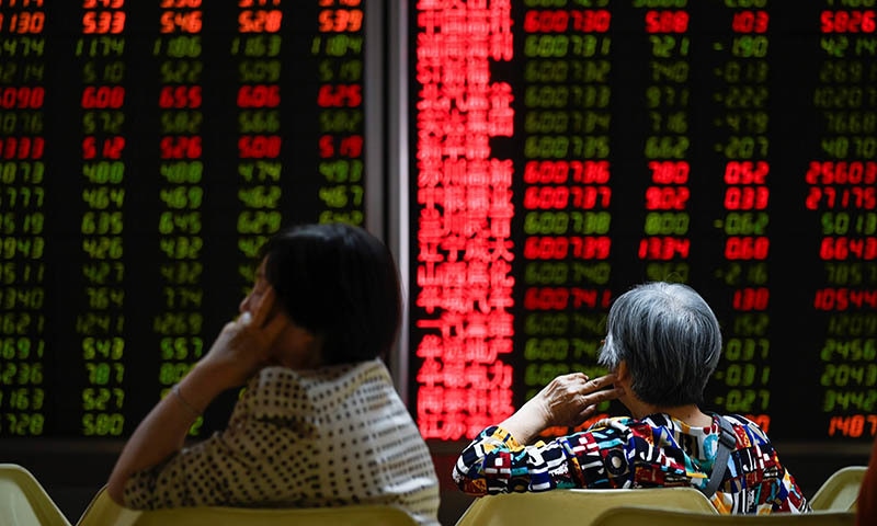 Investors rest on a chair in front of screens showing stock market movements at a securities company in Beijing on May 14, 2019. &mdash; AFP