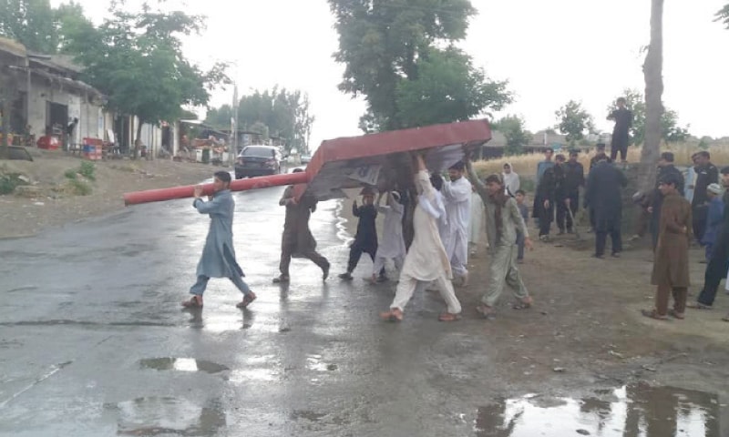 The district administration staffers remove a billboard in Bajaur. &mdash; Dawn