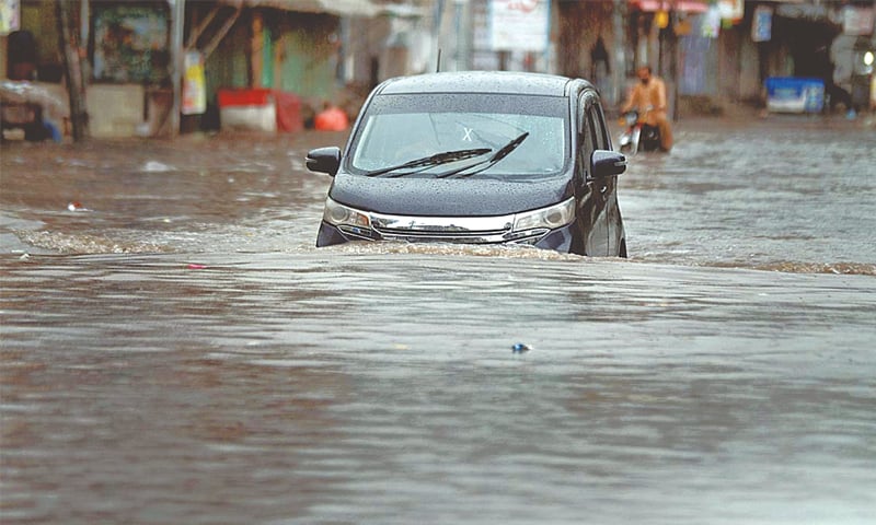 RAWALPINDI: A vehicle passes through standing rainwater in Dhoke Khaba after heavy rain in the city on Friday.—APP