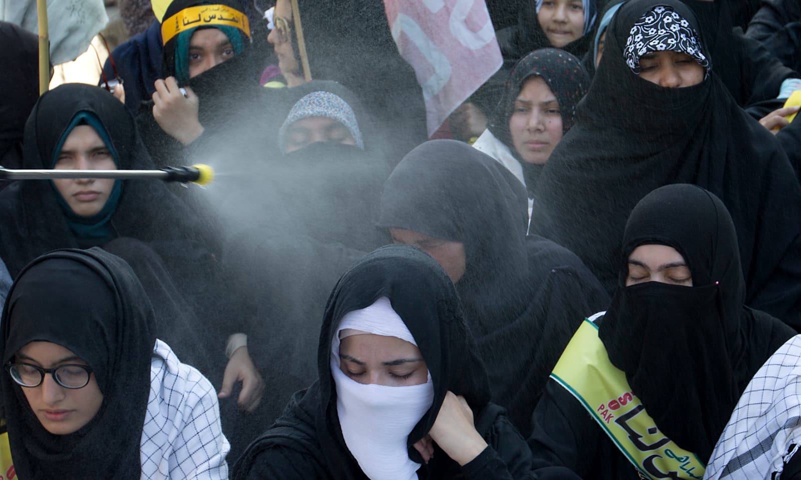 اسلام آباد میں شدید گرمی کے باعث رضا کار ریلی میں شریک خواتین پر پانی کا چھڑکاؤ کر رہے ہیں &mdash; فوٹو: اے پی