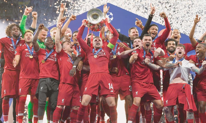 LIVERPOOL captain Jordan Henderson lifts the trophy as his team-mates celebrate after winning the Champions League final.—AFP