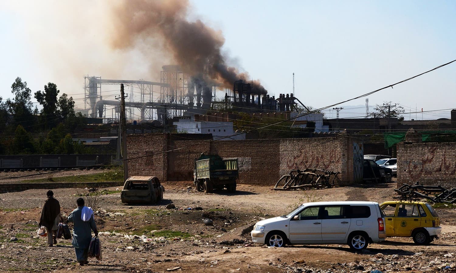 This photograph shows people walking near a factory. &mdash; AFP/File