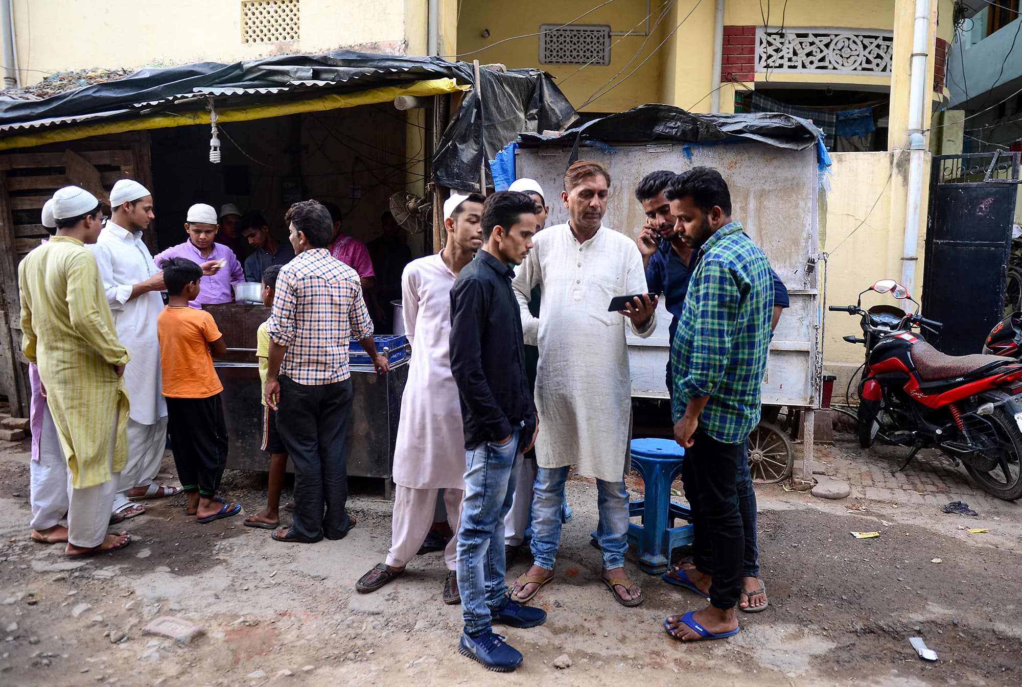 A crowd of Indian men huddles around a cellphone to catch the broadcast in Allahabad. ─ AFP