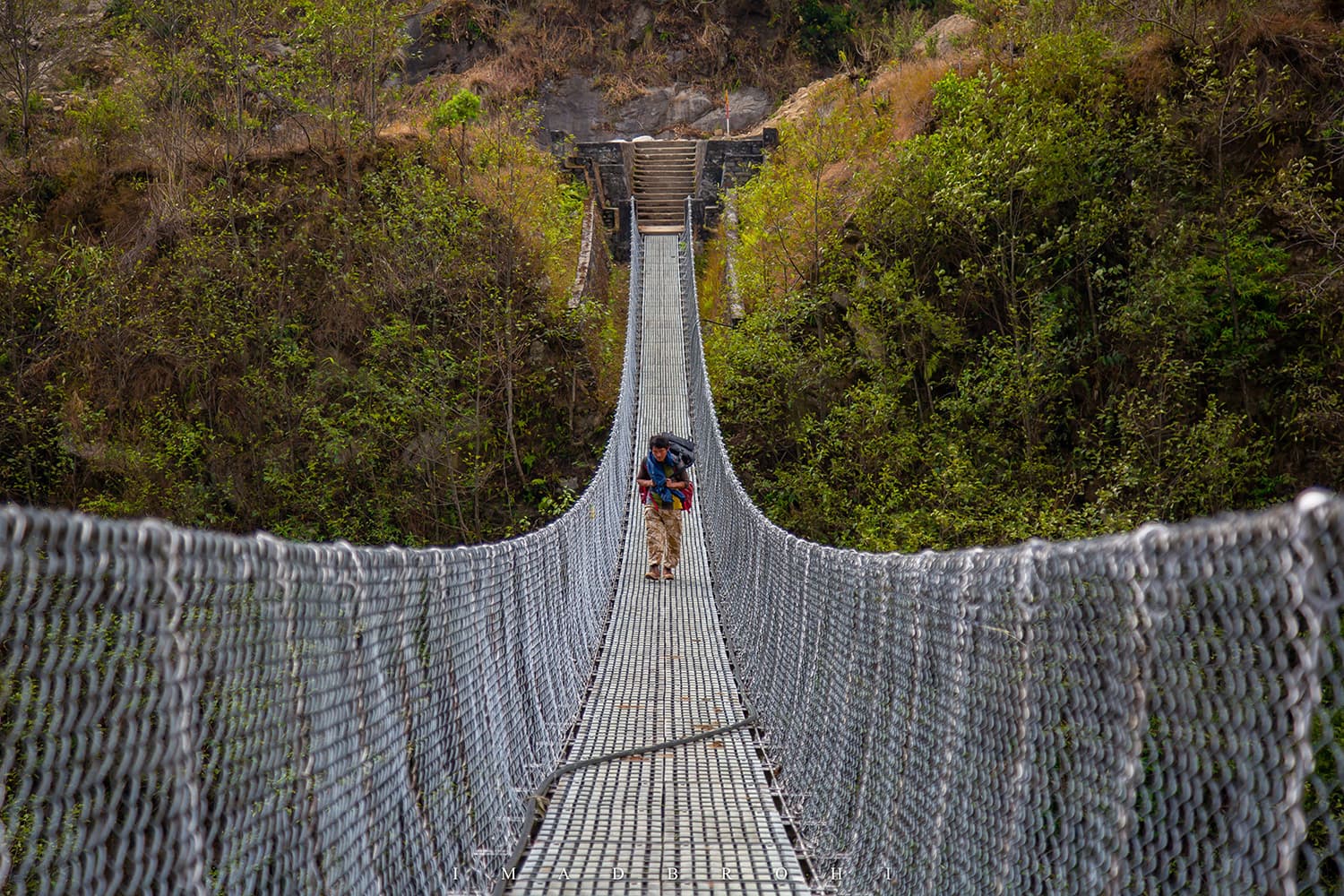 Porter Neema Sherpa crossing a hanging bridge just before Sekathum.