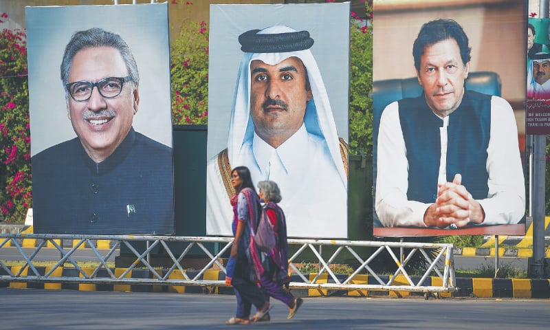 ISLAMABAD: Women walk past the portraits of Qatari Emir Sheikh Tamim bin Hamad Al Thani, President Arif Alvi and Prime Minister Imran Khan on the Constitution Avenue on Friday. The Qatari emir will arrive in Islamabad on Saturday for a two-day visit.—AFP