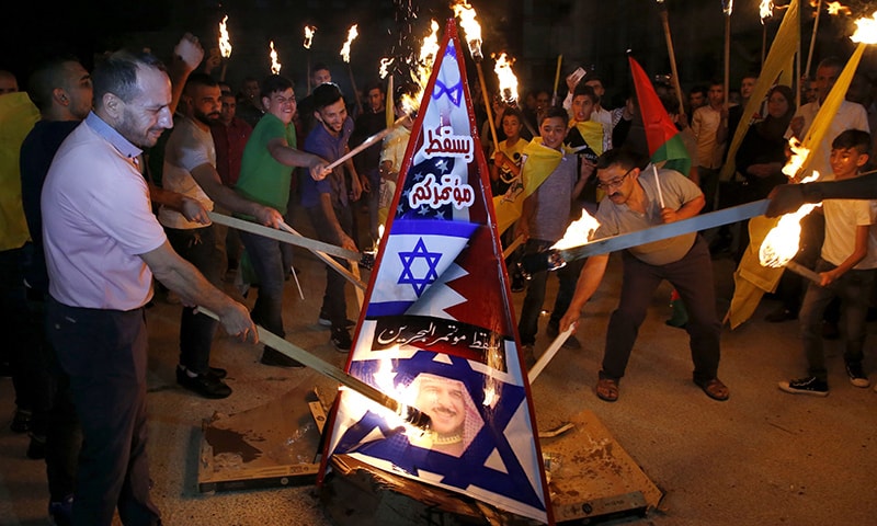 Palestinians burn a structure displaying the Israeli flag and a portrait of King Hamad al-Khalifa of Bahrain during protests against a US-led meeting this week in the Gulf kingdom on the Palestinian-Israeli conflict, in the West Bank city of Hebron on June 24. — AFP