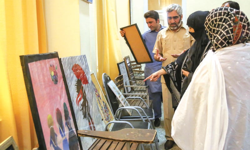 Visitors discuss paintings at the exhibition in University of Swat on Thursday. &mdash; Dawn