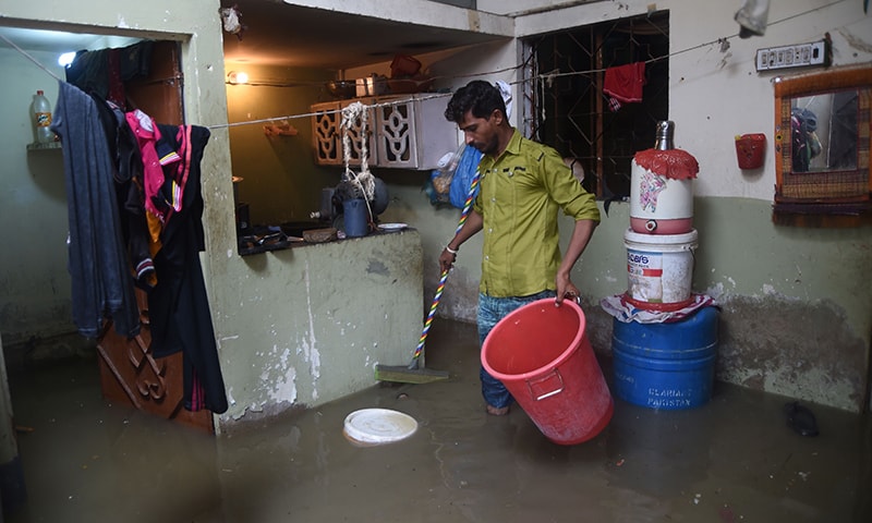 A resident tries to remove rainwater from his house during heavy monsoon rains in Karachi on July 30. — AFP