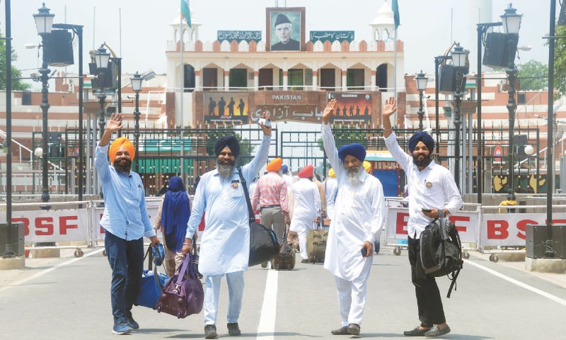 WAGAH BORDER CROSSING: Sikh pilgrims from India wave just before entering Pakistan on Tuesday.—AFP WAGAH BORDER CROSSING: Sikh pilgrims from India wave just before entering Pakistan on Tuesday.—AFP