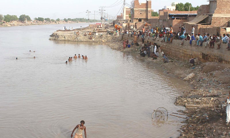 HYDERABAD: Divers search for bodies of two children who drowned in Pinyari Canal on Sunday as relatives and area people wait anxiously on the bank.&mdash;Dawn