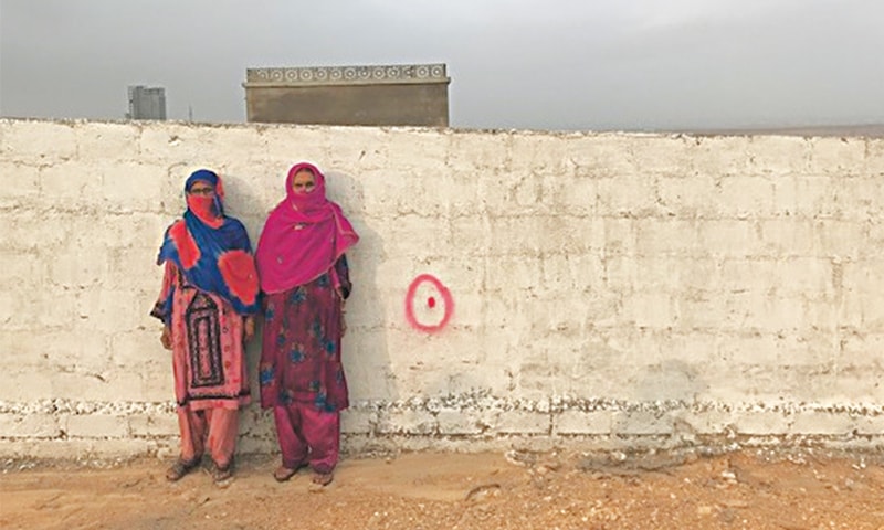 HAJRAH and Hawwa stand against the wall of the latter’s house. The red marker denotes it is soon to be torn down by Bahria.—Photo by writer 