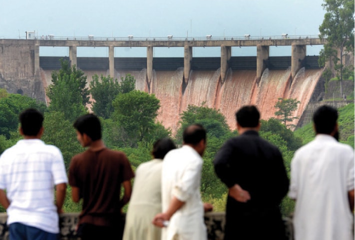 People watch water gushing out of the spillways at Rawal Dam