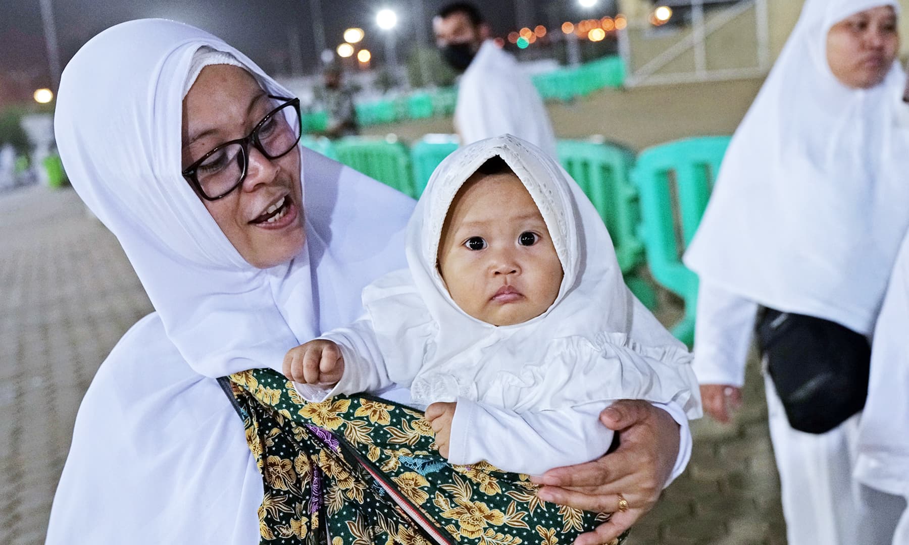 A woman carries her baby as she walks through Mount Mercy on the plains of Arafat during the annual haj pilgrimage. — Reuters