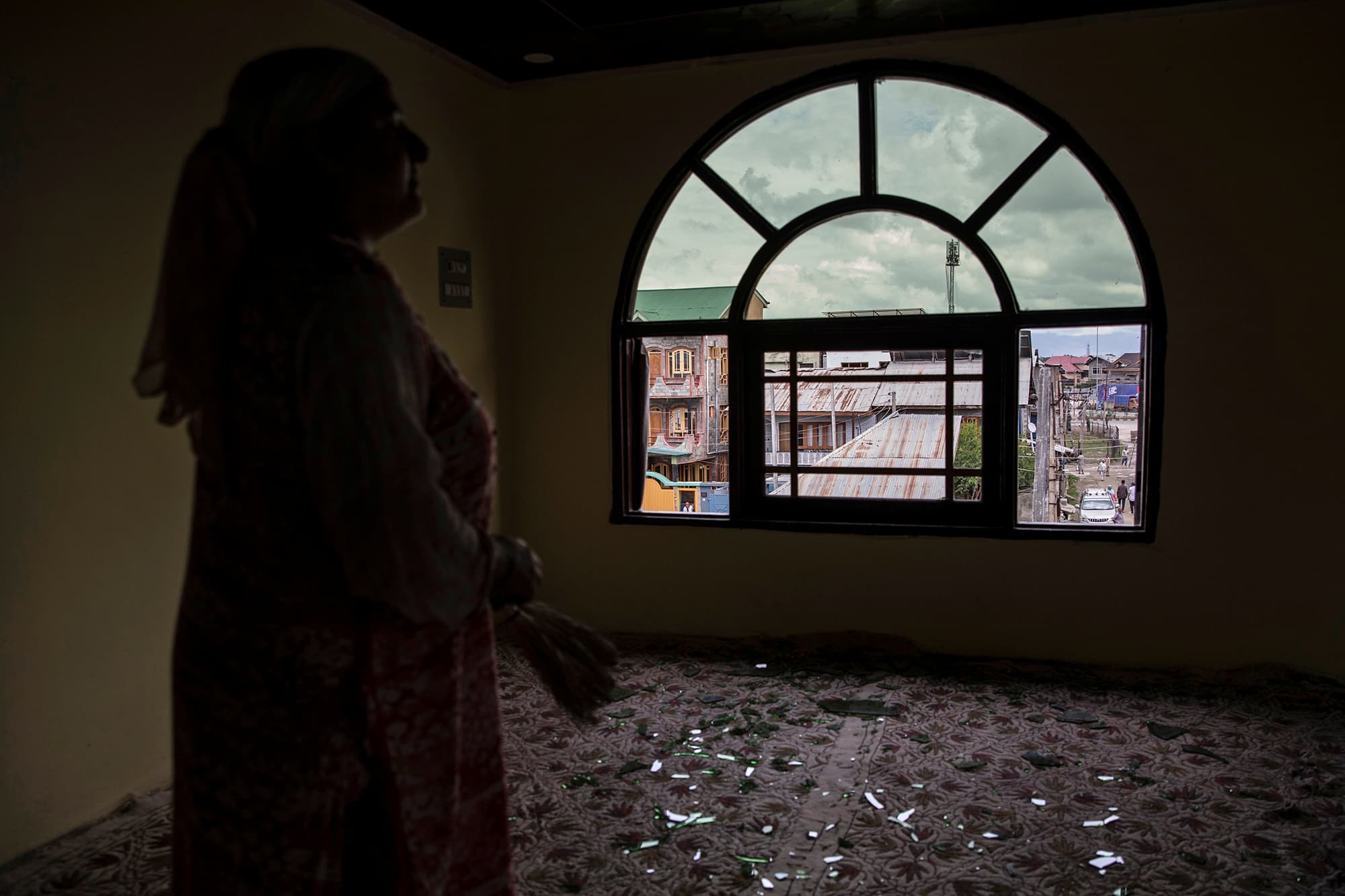 A woman stands next to a broken window of her house that was allegedly damaged by Indian security personnel after clashes between protesters and security forces during curfew in Srinagar. ─ Reuters