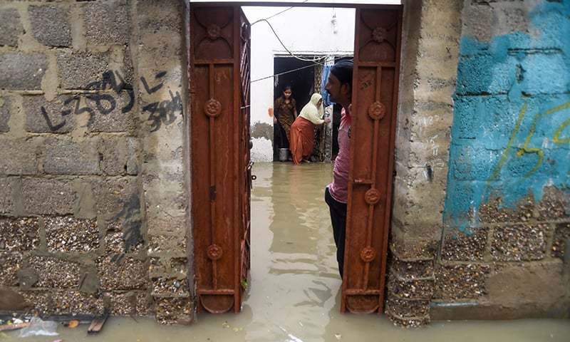 A family shows their flooded house after heavy monsoon rains in Karachi on Aug 11, 2019. — AFP