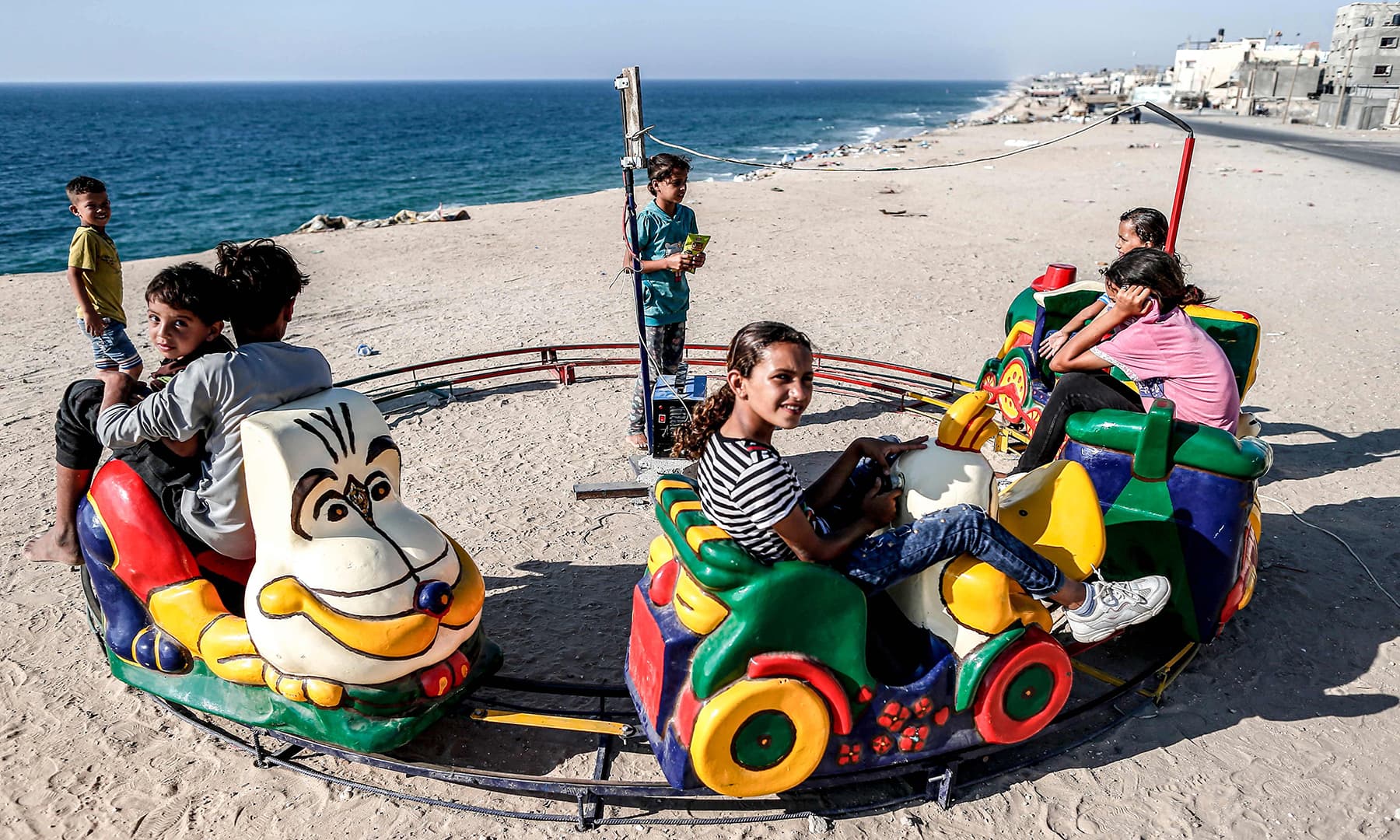 Palestinian children ride on a toy train overlooking the Mediterranean, while celebrating during the third day of Eidul Azha in the Deir al-Balah refugee camp in the central Gaza Strip on Tuesday. &mdash; AFP