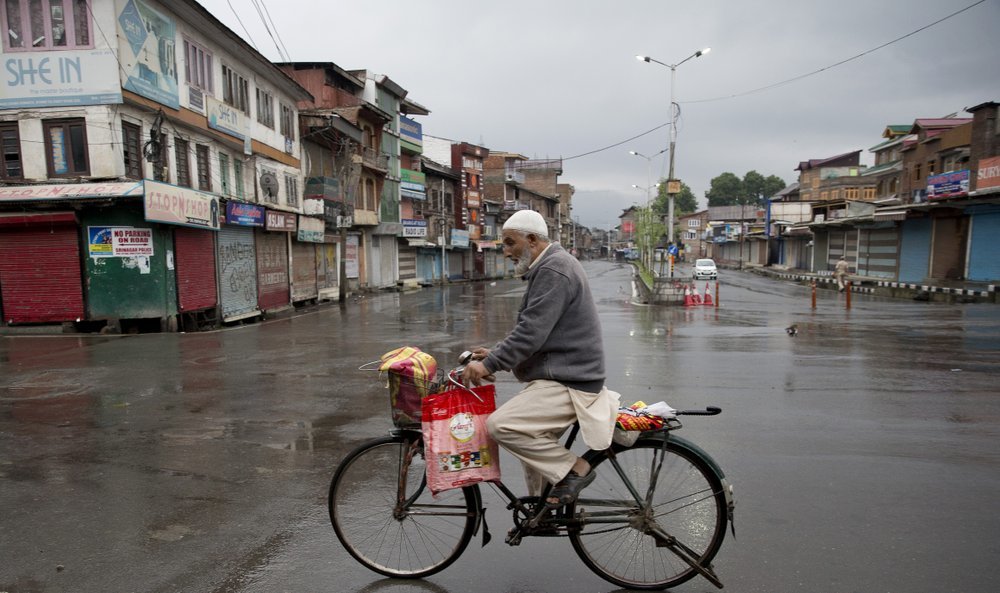 A Kashmiri man rides a bicycle through a deserted street during security lockdown in Srinagar on Wednesday. ─ AP