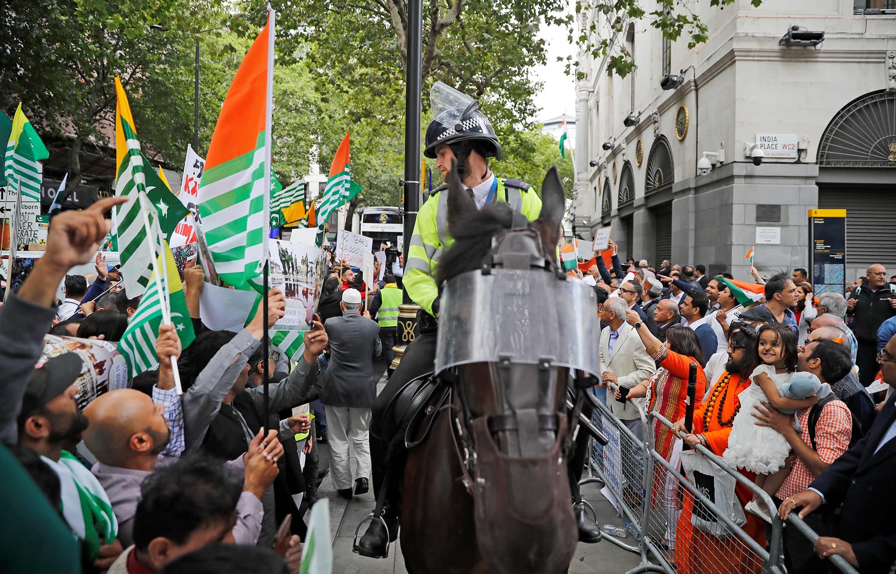 A British mounted police officer sits on his horse between pro-Pakistan (L) and pro-India (R) demonstrators as they protest outside of the Indian High Commision in central London on Thursday. — Reuters