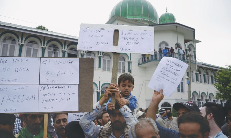 A young boy joins protesters holding aloft placards at a rally against India on Aug 16.—AFP