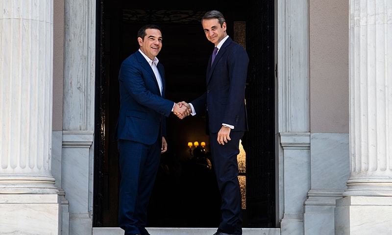 Newly-appointed Greek Prime Minister Kyriakos Mitsotakis (R) shakes hands with former prime minister Alexis Tsipras. — AFP/File