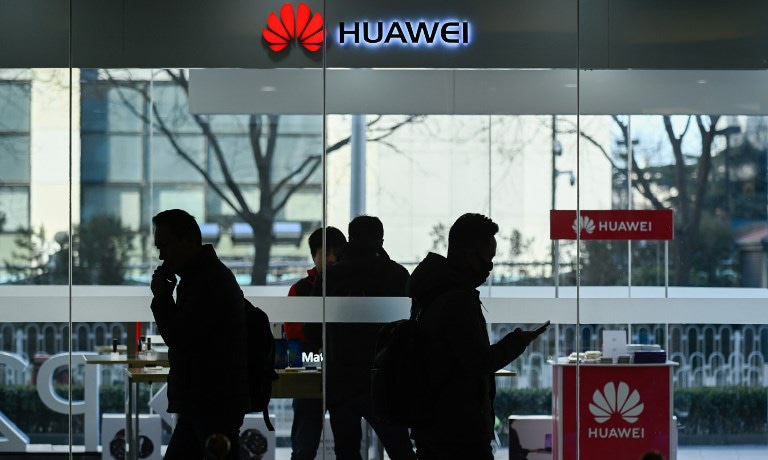 Pedestrians walk past a Huawei store in Beijing on December 28, 2018. — AFP