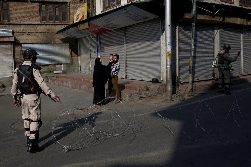 A Kashmiri family waits for a lift to take their sick child to hospital as Indian paramilitary soldiers stand guard near a checkpoint during lockdown in Srinagar on Friday. ─ AP