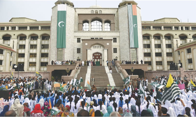 ISLAMABAD: People wave national and AJK flags as Prime Minister Imran Khan arrives at PM Secretariat on Friday.—Tanveer Shahzad / White Star