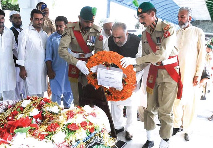 National Assembly Speaker Asad Qaiser lays a floral wreath on the grave of Shaheed Captain Karnal Sher Khan (Nishan-i-Haider) in Swabi on Friday. &mdash; APP