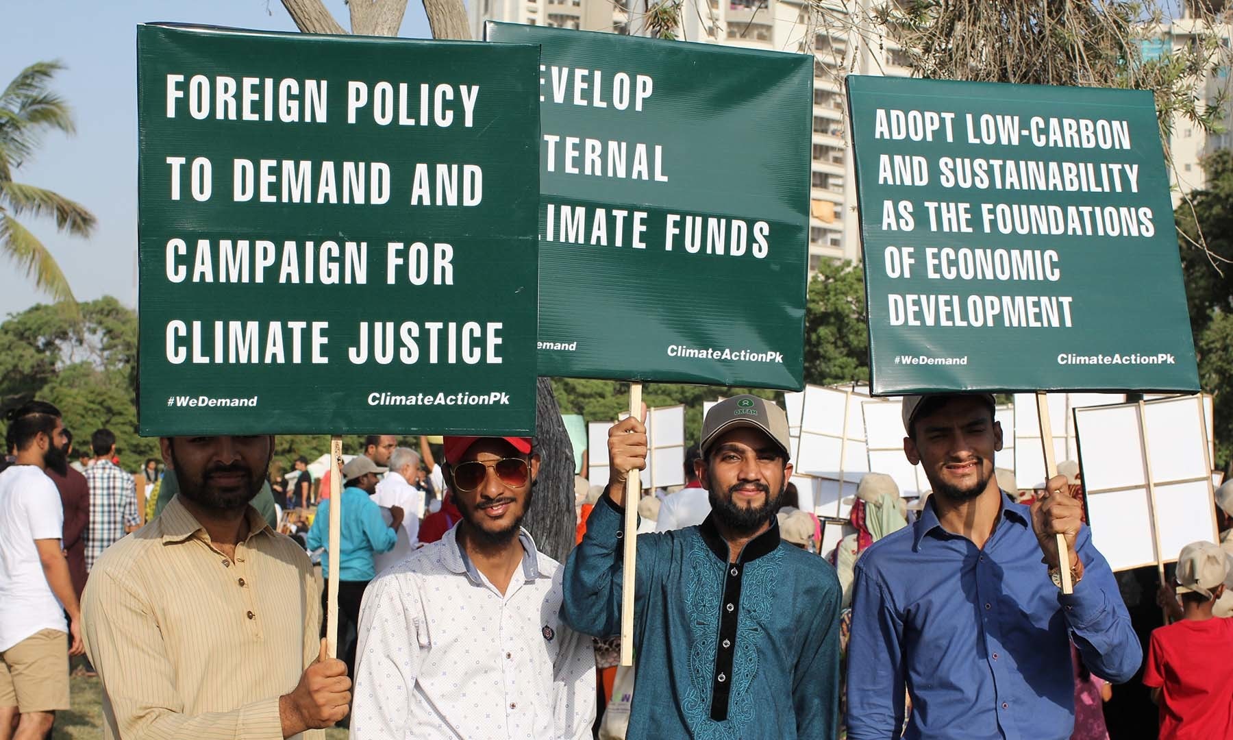 Attendees hold up posters at the climate march in Karachi. — Photo by Kamran Nafees