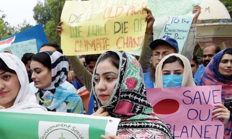 Participants hold placards at a climate march in Peshawar on Friday. — White Star