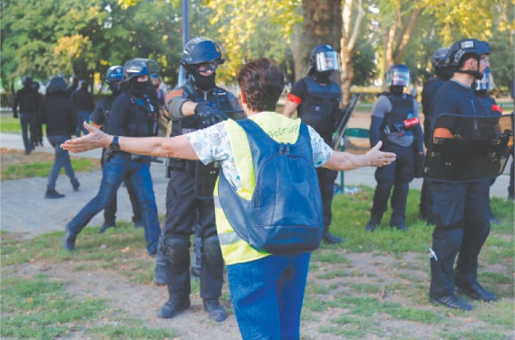 PARIS: A yellow vest demonstrator confronts police officers during a protest on Saturday.—AFP