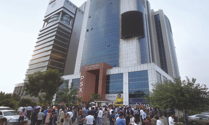 A man stands beside a collapsed building in an earthquake-hit area on the outskirts of Mirpur on Tuesday. (Right) People gather outside their office building after the earthquake was felt in Islamabad.—AFP/AP