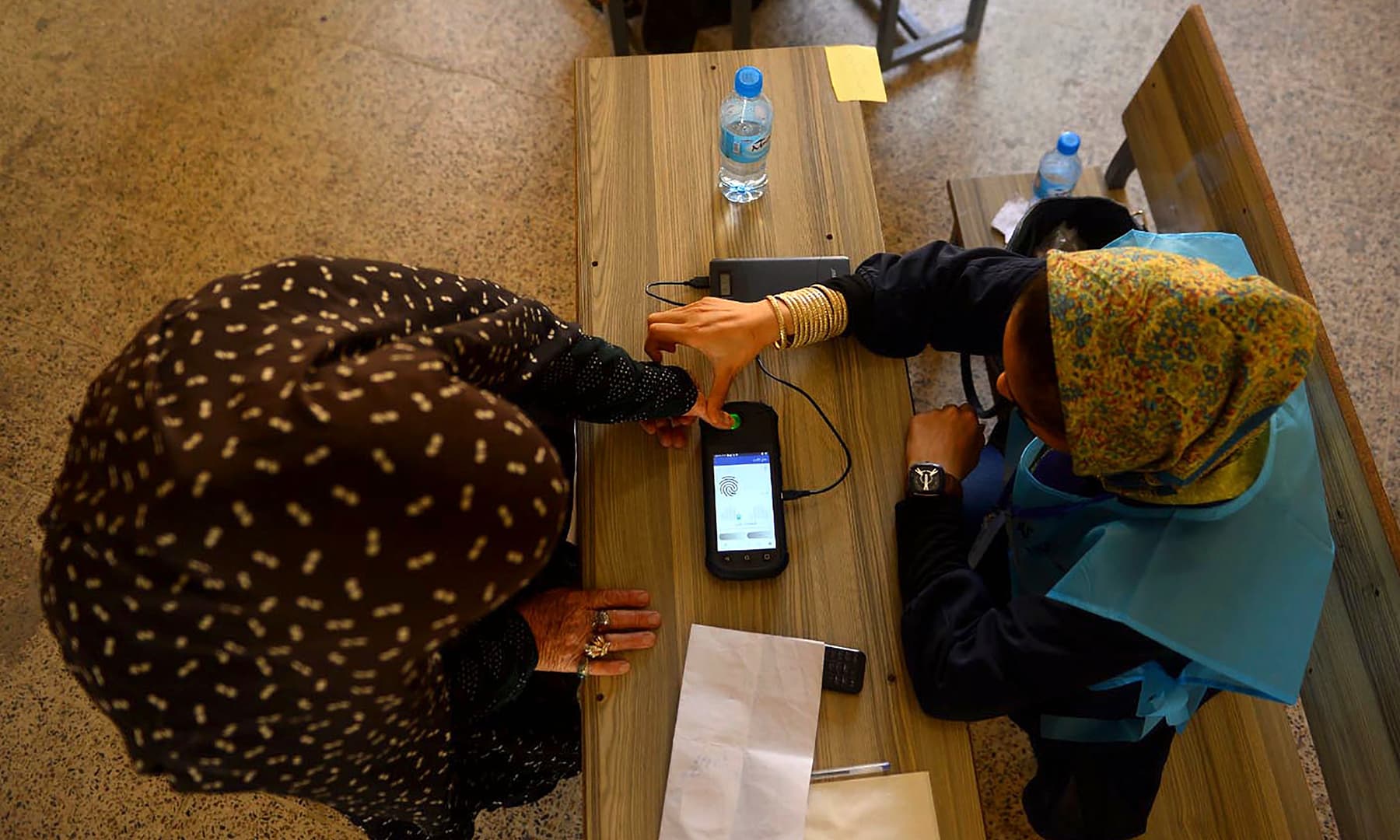 An Independent Election Commission (IEC) official scans a finger of a voter with a biometric device at a polling station in Herat. — AFP