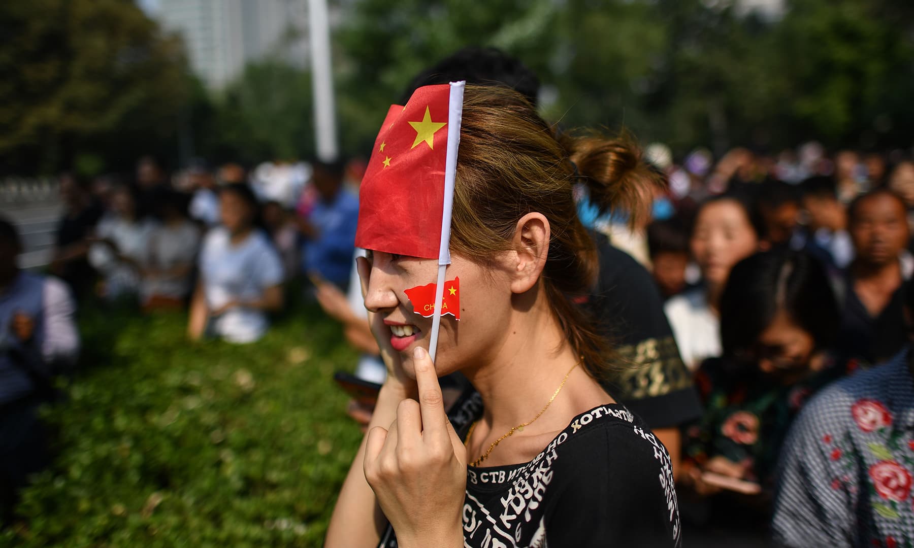 A citizen watches a military parade along the security perimeter established around the official ceremony in Tiananmen Square in Beijing. — AFP