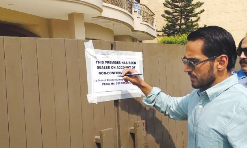 An official of CDA&rsquo;s building control directorate seals a house in E-11 on Wednesday. &mdash; White Star