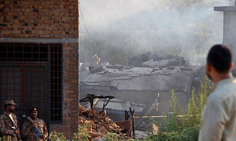 Pakistani soldiers stand guard near a damaged roof after a military aircraft on a training flight crashed in a built-up area in the garrison city of Rawalpindi on July 30, 2019. — Reuters Pakistani soldiers stand guard near a damaged roof after a military aircraft on a training flight crashed in a built-up area in the garrison city of Rawalpindi on July 30, 2019. — Reuters