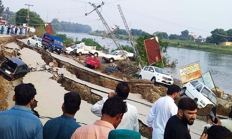 In this file photo, people gather near a heavily damaged road in Mirpur district of Azad Jammu and Kashmir on September 24. — Reuters