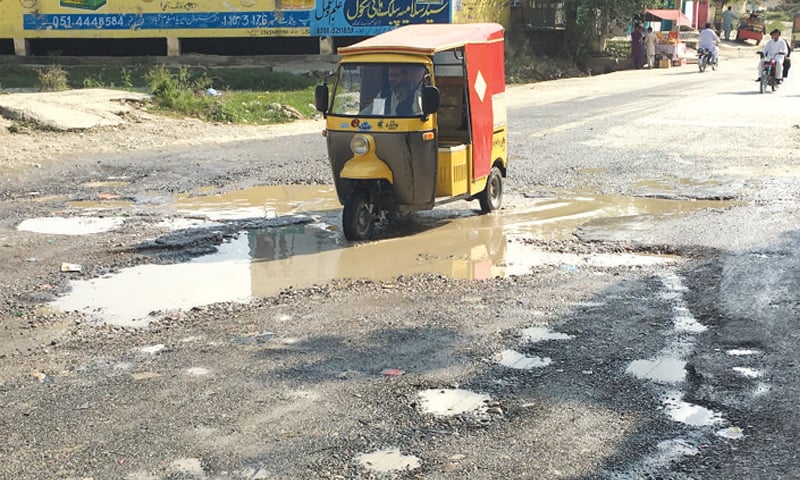 A rickshaw passes through the dilapidated road. &mdash; Dawn
