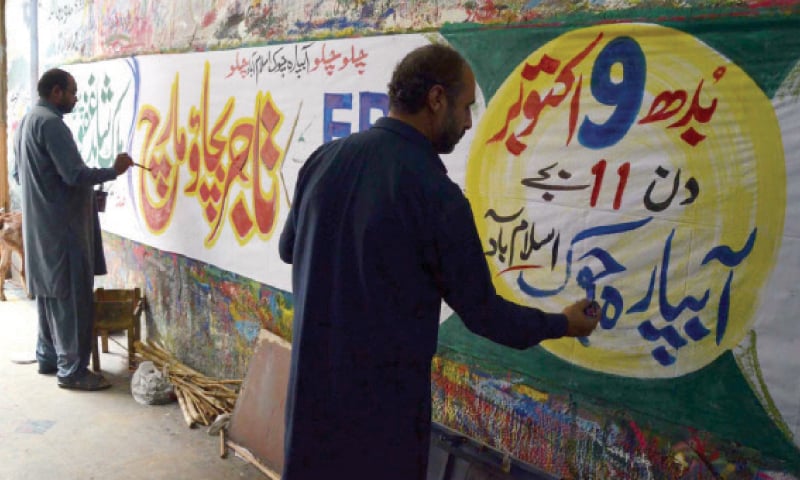 Painters prepare a banner in connection with the traders’ protest in Islamabad. —INP