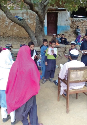 A teacher takes a class in the open in Hanjoo area of Battagram. —Dawn