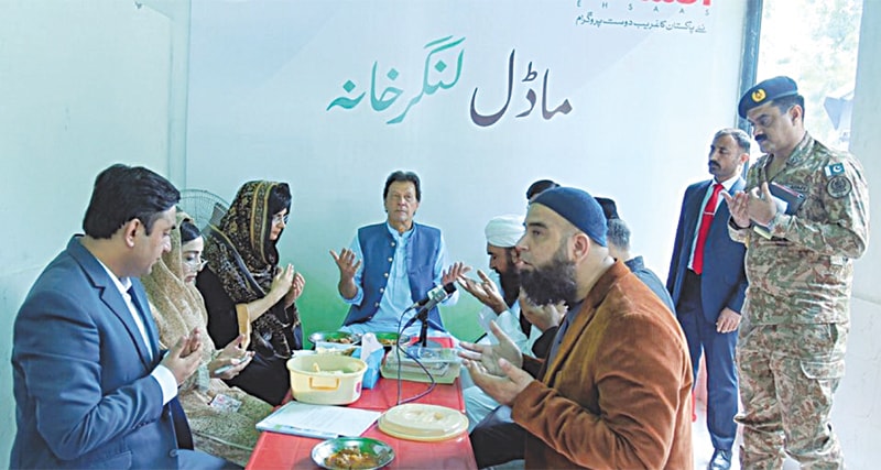 ISLAMABAD: Prime Minister Imran Khan prays before eating food after the inauguration of ‘Model Free Kitchen’ under the Ehsaas programme on Monday.—PID