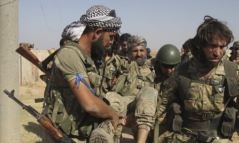 Turkish-backed Syrian opposition fighters evacuate an injured fellow combatant in Tel Abyad, Syria on Saturday, October 12, 2019. — AP